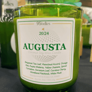 95indies Augusta Candle in a green glass jar with a golf-inspired label, featuring fresh bergamot tea, raincloud accord, and Carolina cherry.