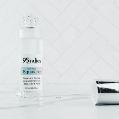 Glass bottle containing squalane which is a hydrating powerhouse with age-well benefits is shown behind a glass dropper containing squalane to display its clarity.