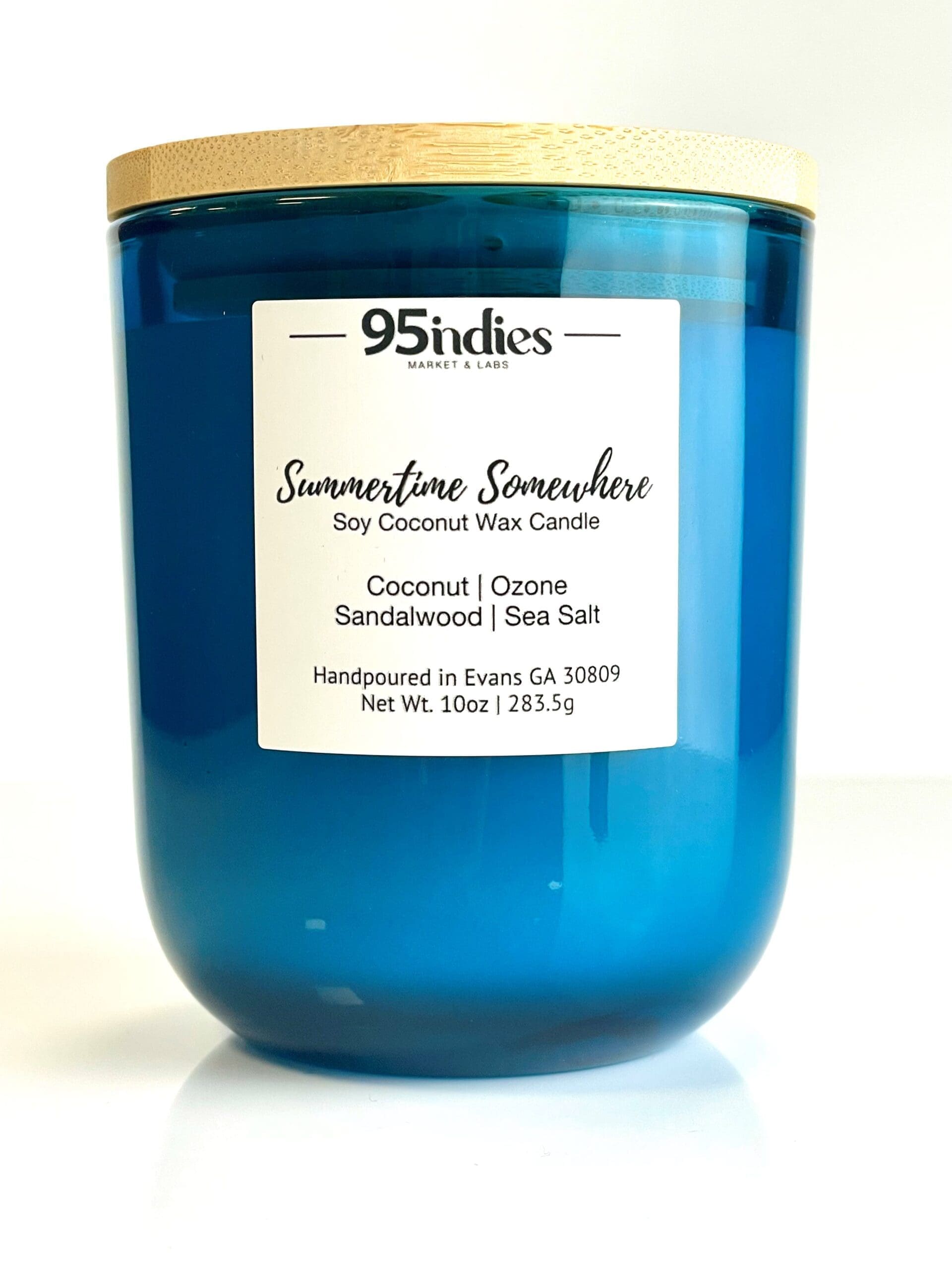 Summertime Somewhere Candle: A luxurious blend of coconut, ozone, sandalwood, and sea salt. Hand-poured in Evans, GA by 95indies Summertime Somewhere soy coconut wax candle in a blue glass jar with a wooden lid, hand-poured by 95indies in Evans, GA.