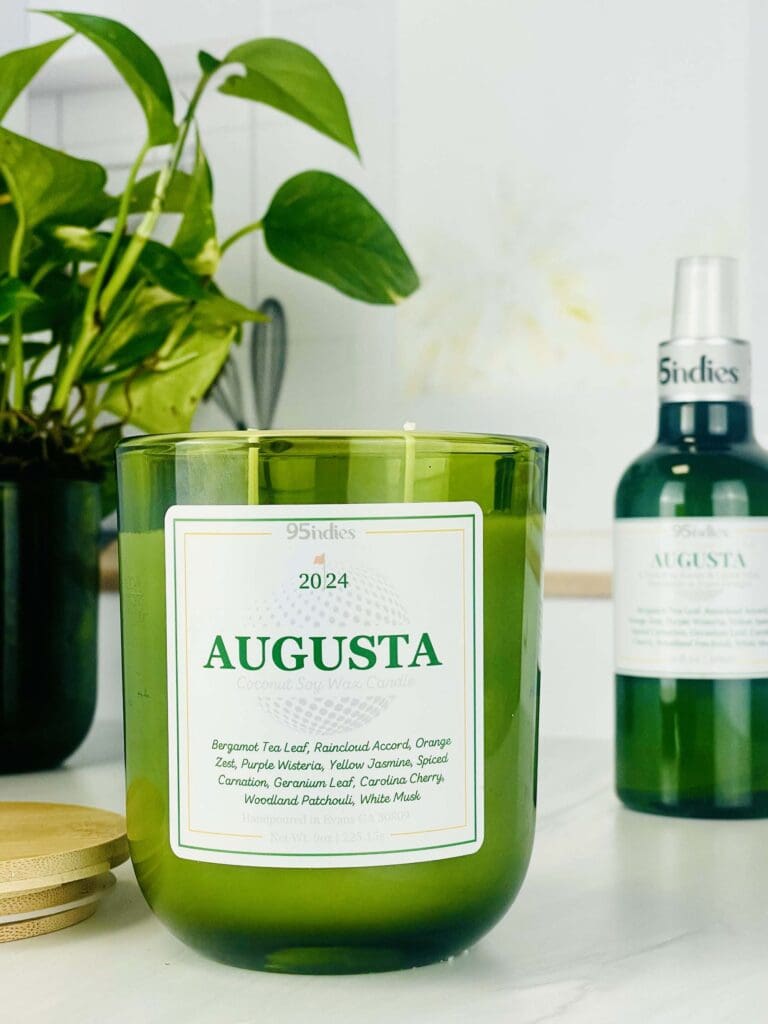 A95indies Augusta Candle and Room Spray on counter with green glass vessels and plant in background