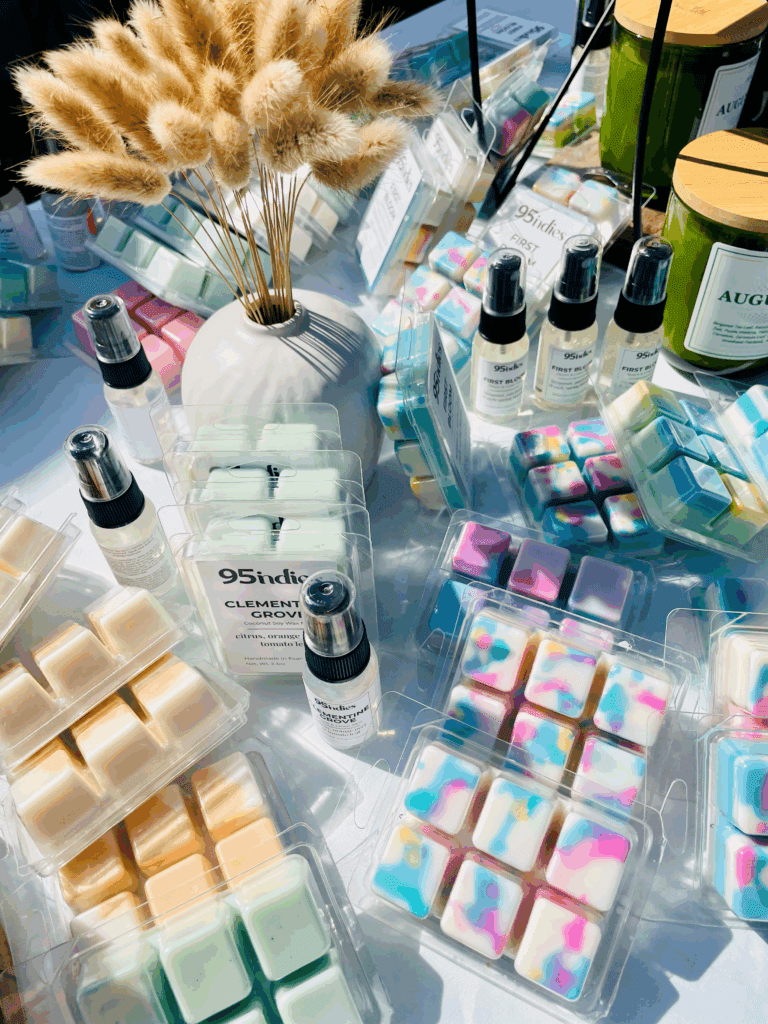 Handmade wax melts, room sprays, and candles by 95indies displayed in natural light with pampas grass.