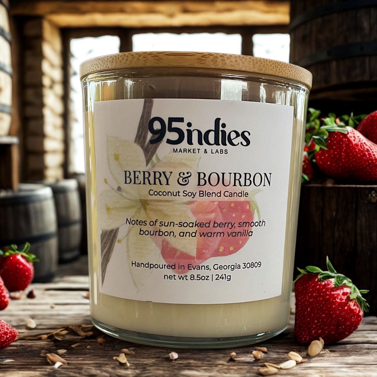 Savor the scent of sun-soaked berries, smooth bourbon, and vanilla in this hand-poured candle crafted in Evans, Georgia. Berry & Bourbon coconut soy candle in glass jar with wood lid, styled with strawberries and barrels in rustic background.