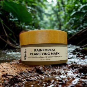 95indies Rainforest Clarifying Mask with bamboo lid, photographed beside a lush stream in a tropical rainforest setting.