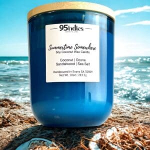Blue 10oz Summertime Somewhere candle by 95indies on a beach with ocean waves and sunshine in the background.