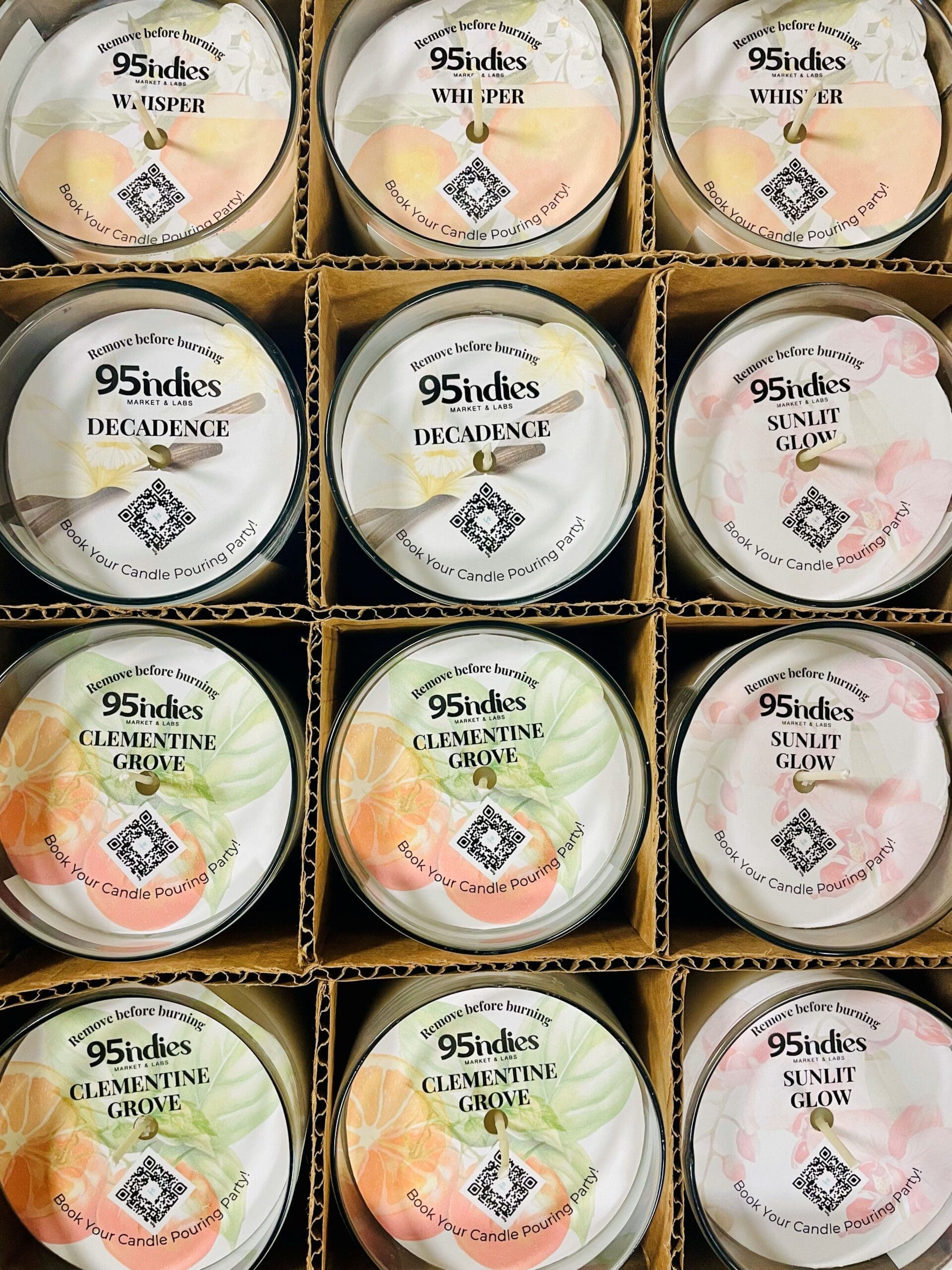 A curated box of twelve 95indies candles in signature scents—perfect for client gifting, team celebrations, and elegant event favors. Box of twelve 95indies candles in assorted fragrances, including Whisper, Decadence, Clementine Grove, and Sunlit Glow, displayed in individual glass tumblers with branded dustcovers