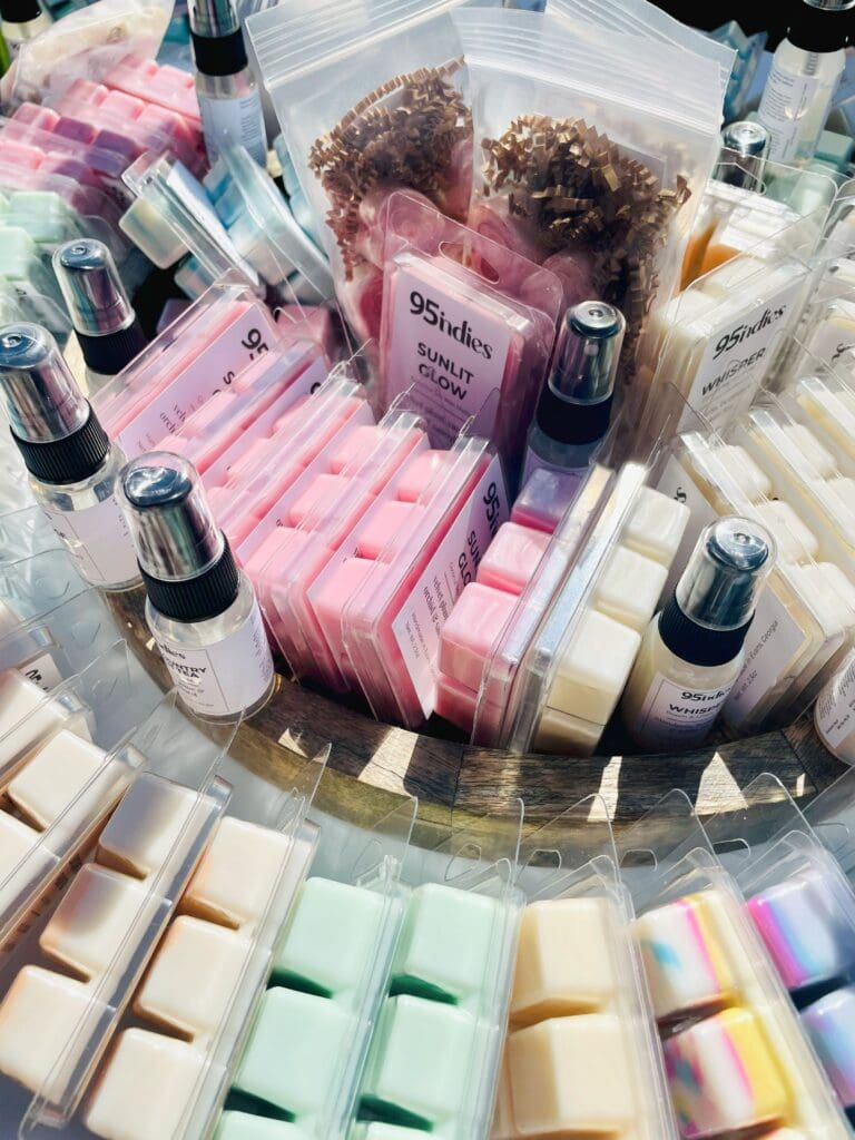 Assorted 95indies hand-poured soy wax melts displayed alongside other home fragrance items in a round basket.