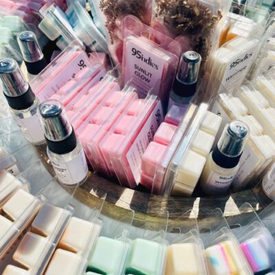 Assorted 95indies hand-poured soy wax melts displayed alongside other home fragrance items in a round basket.