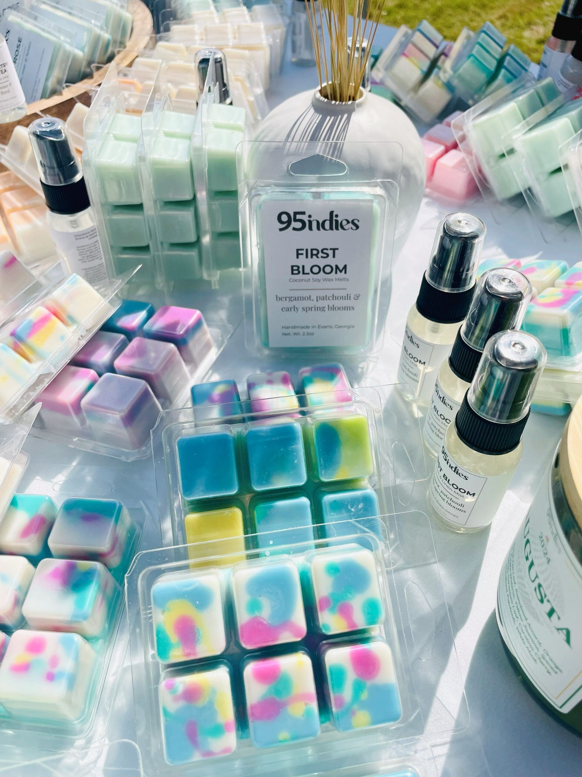 A colorful display of 95indies wax melts hand-poured in Evans, Georgia Assorted 95indies hand-poured soy wax melts displayed on a table alongside other 95indies home fragrance products.