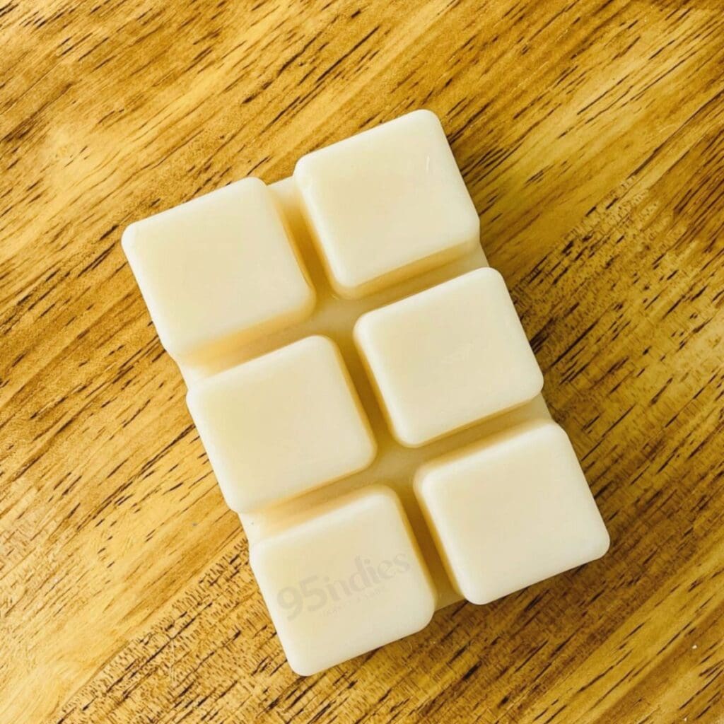 Cream-colored soy wax melts arranged on a wooden surface in soft, natural light.