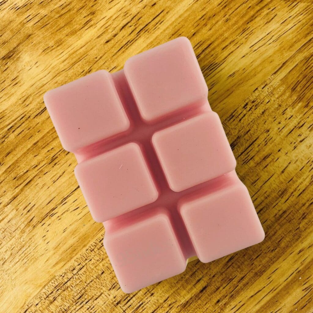 Pinkish pumpkin soy wax melts photographed on a natural wood surface under warm golden light.