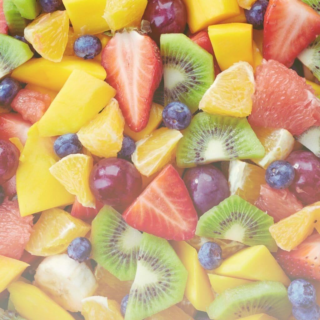 Mixed fruit including strawberries, kiwi, mango, blueberries, and citrus pieces in natural light