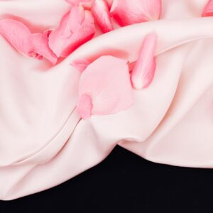 Blush rose petals with soft cashmere fabric in warm natural light
